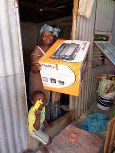 Mama Lucy happily receives a new two-burner/mini-oven from a U.K. donor.